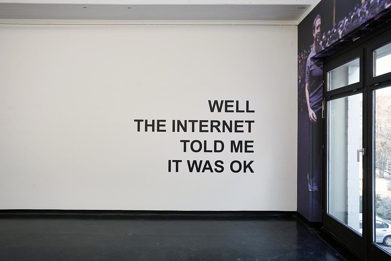 HIGH RES LOW BROW — installation view with the internet photo-wall and a small figure