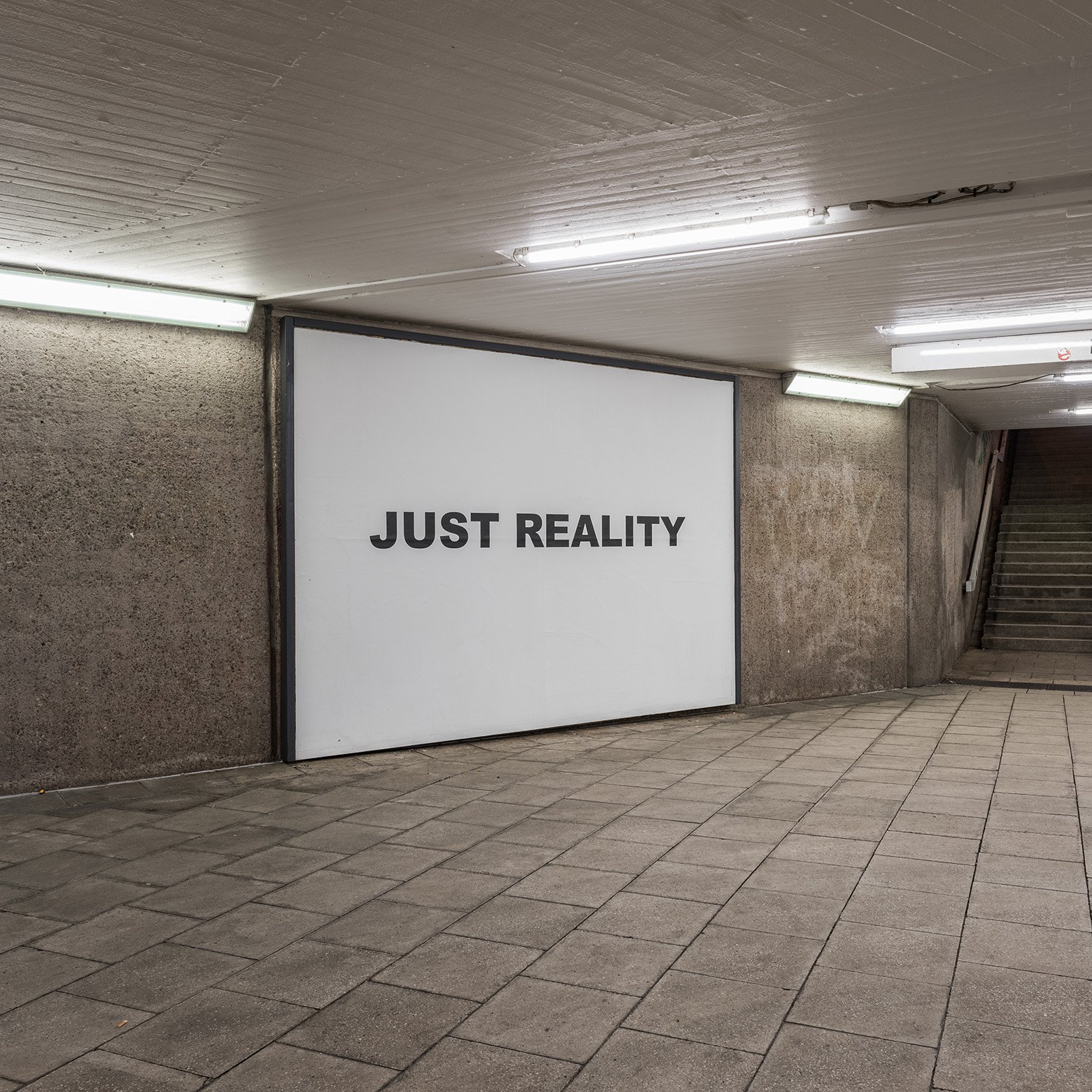 Text work JUST REALITY beside the underpass stairs